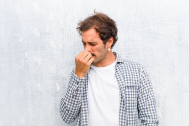 Genç yakışıklı adam iğreniyor, burnundan pis ve tatsız bir kokunun kokusunu almaktan kaçınıyor.