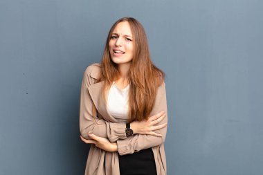 Genç, güzel bir kadın endişeli, hasta, hasta ve mutsuz hissediyor. Ağrılı bir mide ağrısı ya da gripten muzdarip.