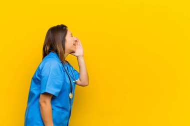 Profil görüntüsü, mutlu ve heyecanlı görünüyor, bağırıyor ve sarı duvara karşı izole edilmiş bir şekilde kopyalama alanı istiyor.