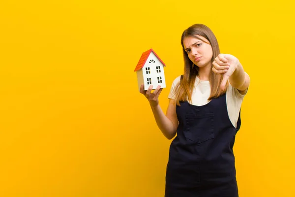 Junge Hübsche Frau Mit Hausmodell Vor Orangefarbenem Hintergrund — Stockfoto