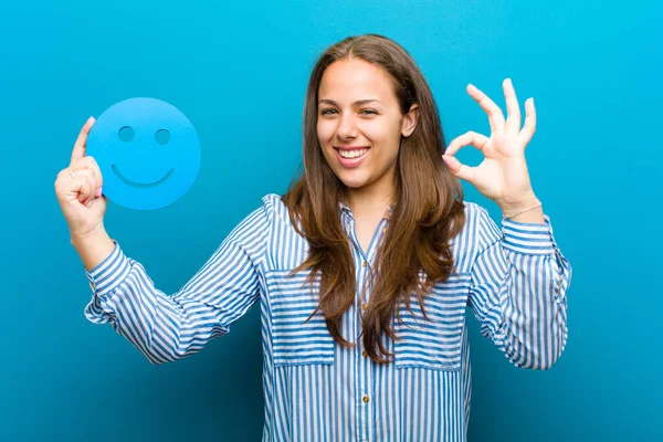 Jonge vrouw met een smiley gezicht tegen blauwe achtergrond — Stockfoto