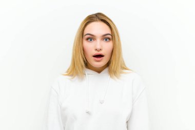 Genç sarışın kadın çok şaşırmış ya da şaşkın görünüyor, ağzı açık beyaz duvara karşı 