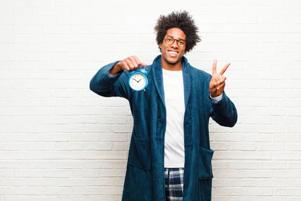 young black man wearing pajamas with an alarm clock