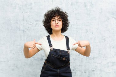 Genç, güzel afro kadın gururlu, pozitif ve iki eliyle göğsünü gösteren