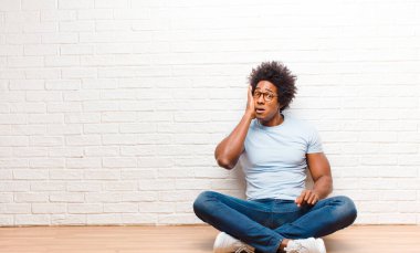 Genç siyahi adam şok olmuş ve şaşkınlık içinde. İnançsızlığını yüzüne vuruyor. Evde yerde ağzı açık oturuyor.