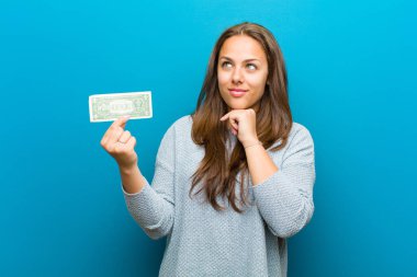 Mavi arka planda faturaları olan genç bir kadın.