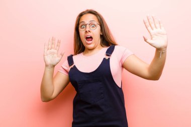 Genç kadın sersemlemiş ve korkmuş hissediyor. Korkutucu bir şeyden korkuyor. Elleri açık ve pembe arka plandan uzak durun diyor.