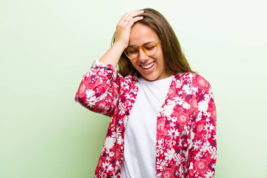 Genç bir kadın gülüyor ve alnına şaplak atıyor. Unutmuşum yoksa yeşil arka planda yaptığım aptalca bir hataydı. 