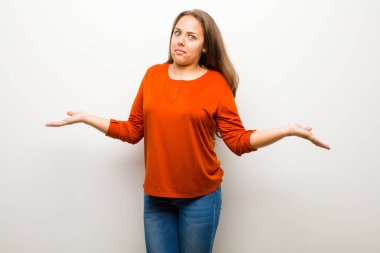 Genç bir kadın kendini cahil ve kafası karışık hissediyor. Hiçbir fikri yok. Beyaz arka plana karşı aptal ya da aptal bir bakışla şaşkına dönmüş.