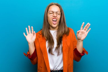 Genç bir kadın kışkırtıcı, agresif ve müstehcen hissediyor. Mavi arka plana karşı isyankar bir tavırla orta parmağını hareket ettiriyor.