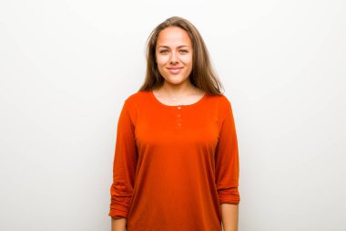 Genç kadın pozitif ve kendinden emin gülümsüyor, tatmin olmuş, arkadaş canlısı ve mutlu görünüyor.