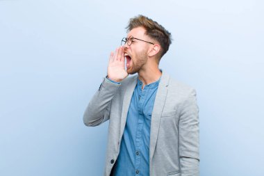 Genç işadamı öfkeyle bağırarak kenardaki boşluğu kopyalamasını söylüyor, elleri ağızlarının yanında mavi arka planda.