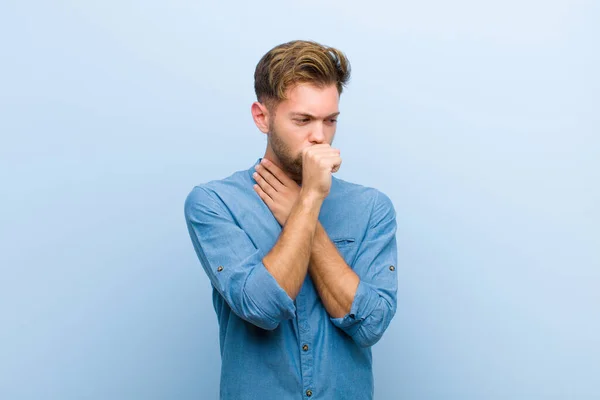 年轻的商人因喉头酸痛和流感症状而感到不适 嘴巴上满是蓝色背景的咳嗽 — 图库照片