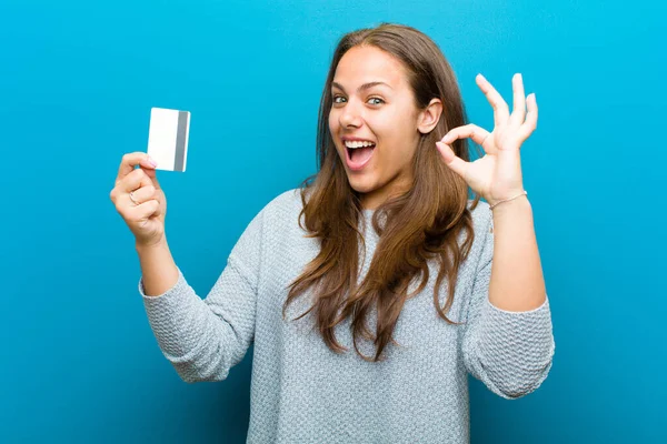 Mujer joven con una tarjeta de crédito sobre fondo azul — Foto de Stock