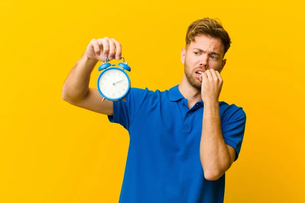 young man with an alarm clock against orange background