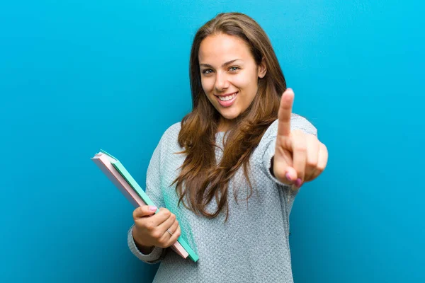 Mladá žena s notebookem proti modrému pozadí — Stock fotografie