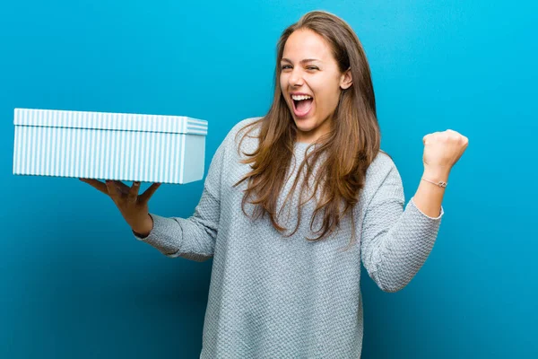 Giovane donna con una scatola sullo sfondo blu — Foto Stock