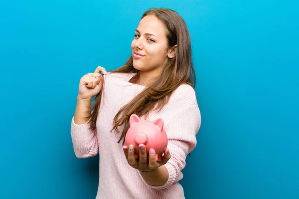 青い背景に対して貯金箱を持つ若い女性 — ストック写真