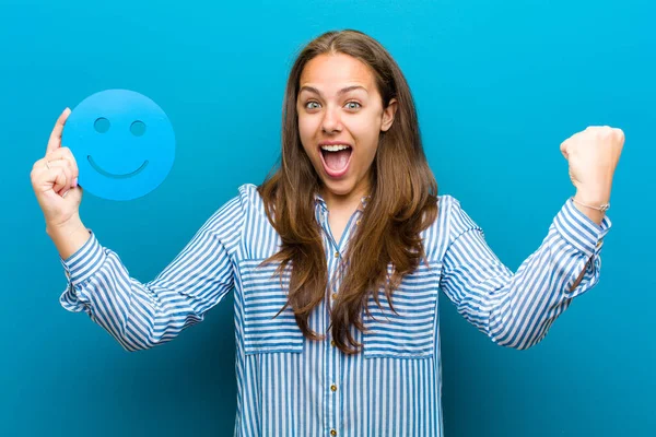 Mujer joven con una cara sonriente sobre fondo azul — Foto de Stock
