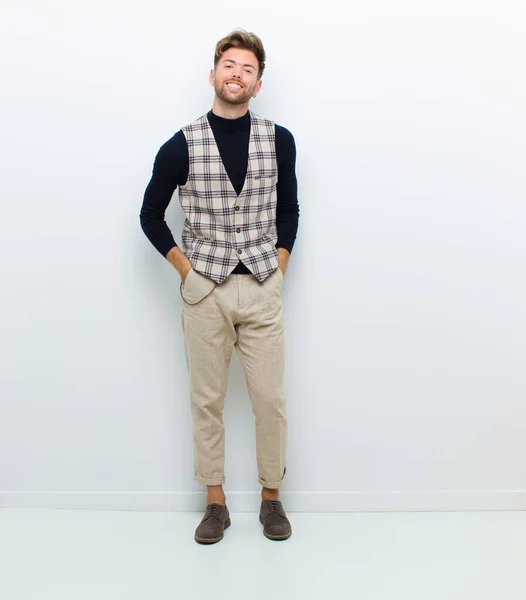 young full body man with a big, friendly, carefree smile, looking positive, relaxed and happy, chilling against white background