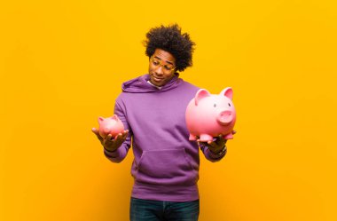 Portakallı sırtında kumbarası olan Afrikalı genç bir Amerikalı.