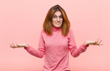 Genç, güzel bir kadın kendini cahil ve kafası karışık hissediyor. Hangi seçeneği seçeceğinden emin değil. Pembe arka planda merak ediyor.