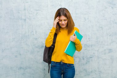 Genç öğrenci kadın konsantre, düşünceli ve ilham verici görünüyor, beyin fırtınası yapıyor ve elleri alnında grunge duvar arkasını hayal ediyor.