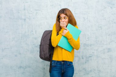 Genç bayan endişeli, gergin, stresli ve korkmuş görünüyor. Tırnaklarını yiyor ve arka plandaki grunge duvarına karşı yanal fotokopi alanı arıyor.