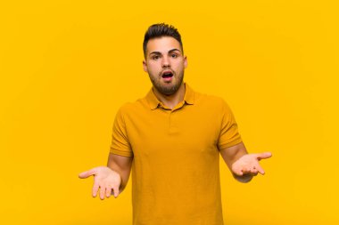 Genç İspanyol adam, turuncu duvara karşı inanılmaz bir sürprizle şaşkın ve şaşkın bir şekilde ağzı açık kaldı.