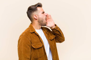 Genç İspanyol adam öfkeyle ve yüksek sesle bağırarak kenardaki boşluğu kopyalamak için, elleri ağızın yanında izole edilmiş arka plana karşı