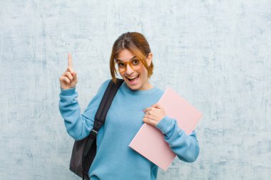 Genç bayan kendini gururlu ve şaşırmış hissediyor, özgüvenini gösteriyor, grunge duvarına karşı kendini başarılı hissediyor.