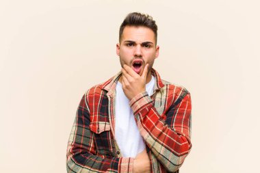 Ağzı ve gözleri açık, eli çenesinde genç İspanyol bir adam, nahoş bir şok geçiriyor, izole bir arka plana karşı ne ya da wow diyor