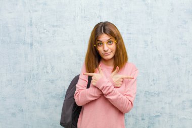 Kafası karışmış, güvensiz ve zıt yönlere bakan genç bir kadın. Grunge Wall arka planına karşı şüpheleri var.