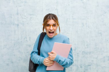 Genç bayan öğrenci korkmuş ve şok olmuş hissediyor, ağzı ardına kadar açık grunge duvarına karşı şaşkınlık içinde