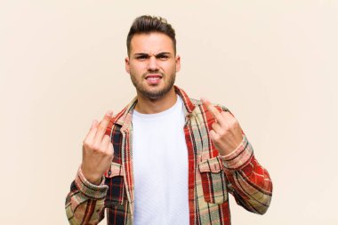 Genç İspanyol adam kışkırtıcı, agresif ve müstehcen hissediyor, izole edilmiş arka plana karşı isyankar bir tavırla orta parmağını hareket ettiriyor.