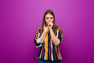 Gırtlağı ağrıyan ve grip belirtileri gösteren, ağzı mor arka planda öksüren genç ve güzel bir kadın.