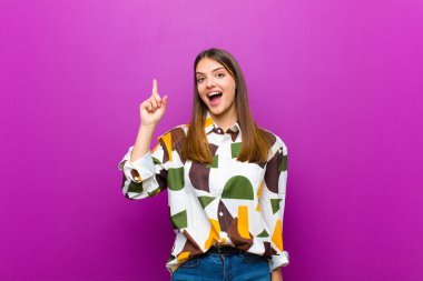 Genç ve güzel bir kadın bir fikri fark ettikten sonra mutlu ve heyecanlı bir dahi gibi hissediyor, neşeli bir şekilde parmağını kaldırıyor, eureka! mor arkaplan