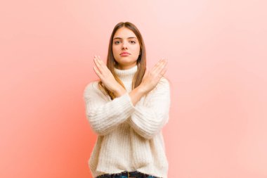 Genç ve güzel bir kadın senin bu tavırlarından rahatsız ve bıkkın görünüyor. Yeter artık! Eller önde çapraz, pembe arka planda durmanı söylüyor.