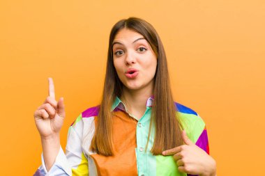 Genç ve güzel bir kadın gururlu ve şaşırmış hissediyor, kendine güvenen, düz arkaplan karşısında izole edilmiş bir numara gibi hisseden, başarılı bir kadın.