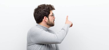 Genç yönetici ayakta duruyor ve nesneye işaret ediyor kopyalama alanı, beyaz duvara karşı dikiz açısı