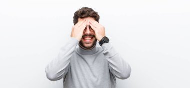 Genç yönetici gülümsüyor ve mutlu hissediyor, iki eliyle gözlerini kapatıyor ve beyaz duvara karşı inanılmaz bir sürpriz bekliyor.