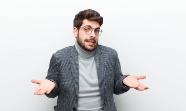 Genç bir yönetici kendini cahil ve şaşkın hissediyor. Hangi seçeneği seçeceğinden emin değil. Beyaz duvara karşı merak içinde.