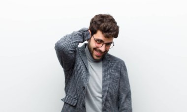 Genç yönetici neşeli ve tesadüfen gülümsüyor, beyaz duvara karşı pozitif, mutlu ve kendinden emin bir bakışla yumruk yumruğa bakıyor.