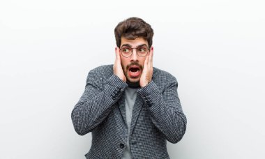 Genç yönetici mutlu, heyecanlı ve şaşırmış hissediyor, yüzünü beyaz duvara dönük bir şekilde yana bakıyor.