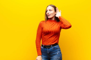 Genç, güzel bir kadın gülümsüyor, tuhaf bir şekilde yan tarafa bakıyor, dedikodu dinlemeye çalışıyor ya da turuncu arka plandaki bir sırrı duymaya çalışıyor.