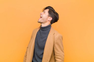 Genç yakışıklı adam öfkeyle bağırıyor, agresif bir şekilde bağırıyor, stresli ve sinirli görünüyor.