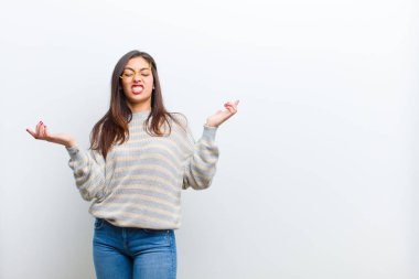 Genç, güzel bir kadın aptal, deli, kafası karışık, kafası karışmış bir ifadeyle omuz silkiyor. Sinirli ve cahil bir şekilde beyaz duvara yaslanıyor.