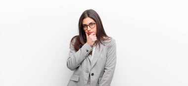 Genç, güzel bir kadın ciddi, şaşkın, kararsız ve düşünceli görünüyor. Seçenekler veya beyaz duvarda izole edilmiş seçenekler arasında şüpheci.