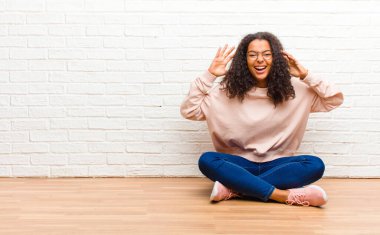 Genç Afrikalı Amerikalı siyahi kadın panik ya da öfke içinde bağırıyor, şok olmuş, korkmuş ya da öfkeli, elleri başının yanında.