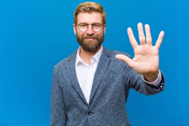 Gülümsüyor ve dost canlısı görünüyor, 5 ya da 5 numarayı gösteriyor, el önde, geriye doğru sayıyor.